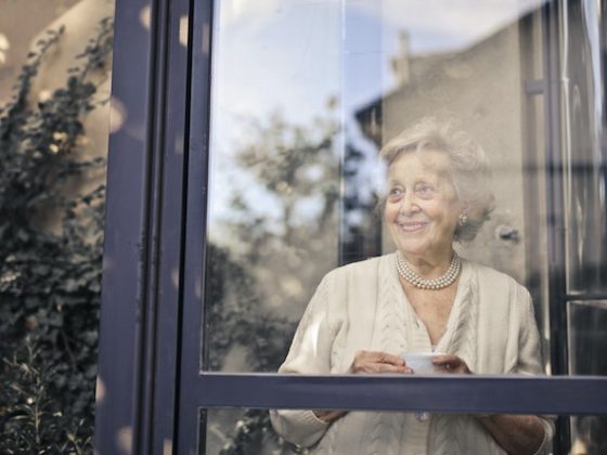 Older Woman looking outside the window during sunny day